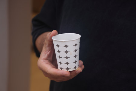 Mockup of male hand holding a Coffee paper cup isolated on light gray backgroundの写真素材