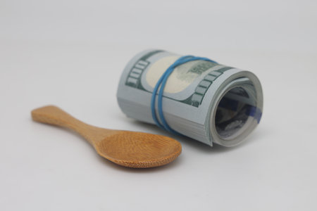 Wooden spoon on the background of hundred-dollar bills. The concept of the high cost of foodの写真素材