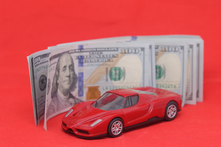 Toy car and money on a red background. Concept of buying a carのeditorial素材