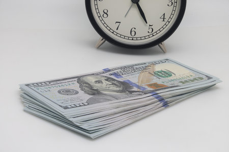 Time is money concept. Alarm clock and dollars on white background. Focus stackingの写真素材