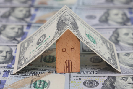a toy house is covered with banknotes, home insurance, mortgage, a symbol of material well-beingの写真素材