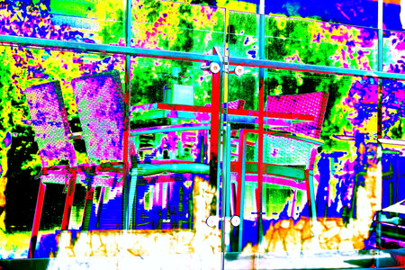 Table and wicker chairs in a cafe on the terrace of a restaurant, behind glass, behind a large glass window reflecting the view outside the cafe for backgroundの写真素材