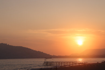 beautiful sunset on the sea. Pier on the beach. mountain view. City skyline, Alanya, Turkiye, May 2023.の写真素材