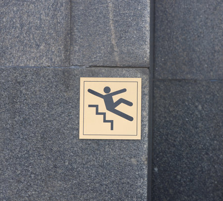 warning sign on a dark granite wall, slippery stepsの写真素材