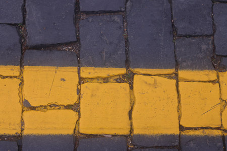road markings on road paving stones, yellow paint on dark paving stonesの写真素材