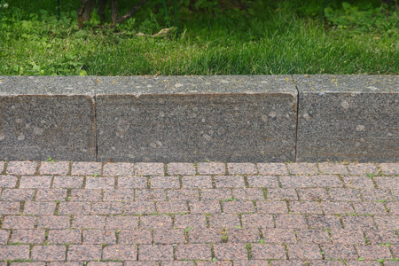 granite curb on green lawn, cobblestone pavement, gray curbstoneの写真素材