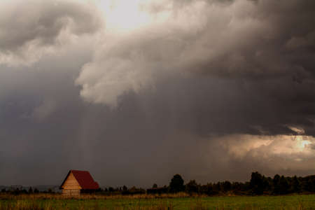 sky black and red color cloud and house in the fieldの写真素材