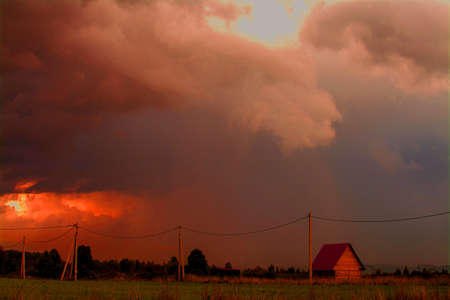 sky black and red color cloud and house in the fieldの写真素材