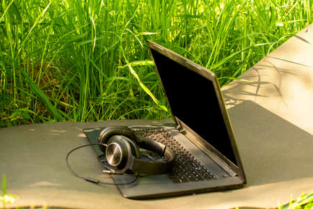 headphones and laptop on a background of grassの写真素材