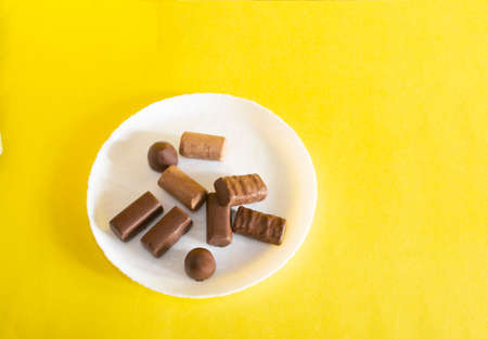 chocolate candies in a plate on a colored background