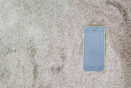 green smartphone on the sand.