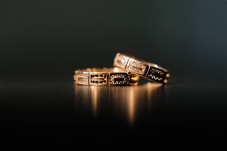 Pair of gold wedding rings on dark background.の写真素材