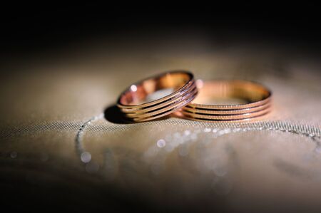 Pair of gold wedding rings on a pillow.