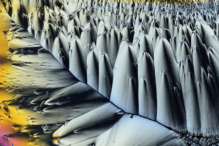 Photo through a microscope of crystals grown from a solution of ascorbic acid in alcohol. Polarized light technology. Abstract art wallpaper. Background for design.の写真素材