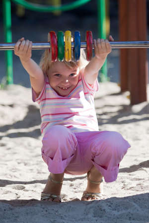 Little girl on the playground having fun at summer time.