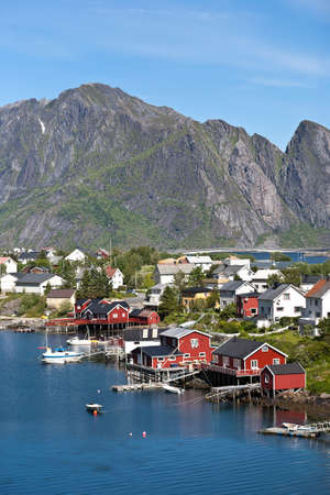 Lofoten islands with typical red fishing hut and towering mountain peaks