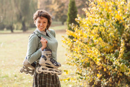 Girl relaxing in autumn park riding on roller skates.