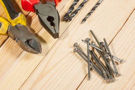 Assorted work tools with nails in the foreground.の写真素材