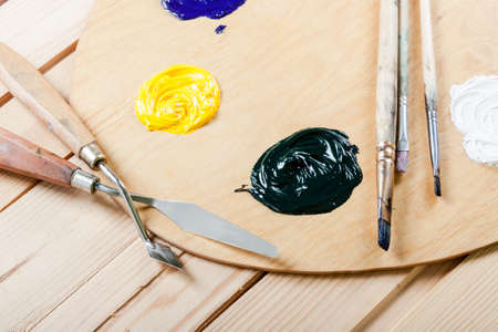 Palette with oil paint and brushes, on the wooden background.の写真素材