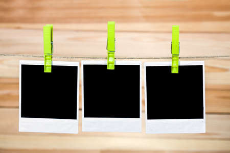 Three black instant photo, hanging on the clothesline on wooden background.