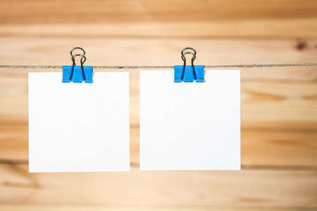 White paper cards hanging on a rope, on a wooden background.の写真素材