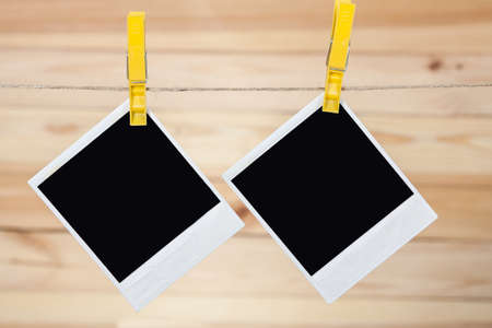 Black instant photo, hanging on the clothesline on wooden background.の写真素材