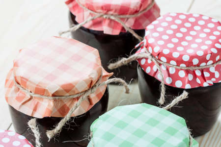 Jar with a strawberry jam on a wooden background.
