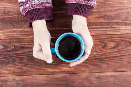 Woman holding hot cup of tea on wooden background.の写真素材