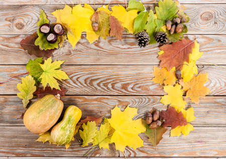 Frame of autumn leafs with pumpkins on wooden background.