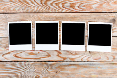 Black instant photo on a wooden background. Old vintage photo card and old table. Photo card background.の写真素材