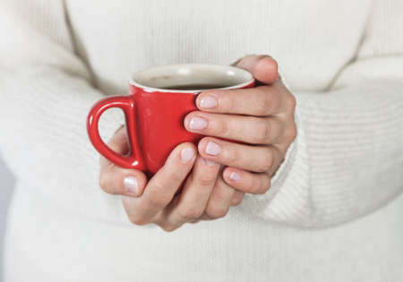 Cup of tea or coffee in female hands close up. Cold weather concept.の写真素材