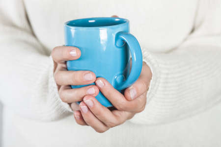 Cup of tea or coffee in female hands close up. Cold weather concept.