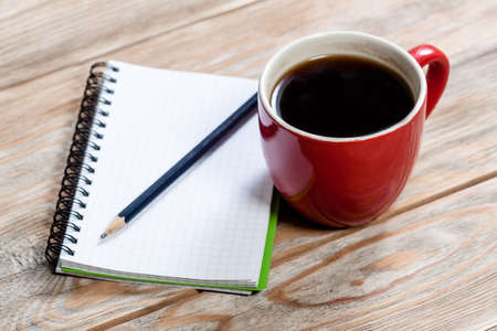 Notebook and cup of coffee on wooden table. Business concept.の写真素材