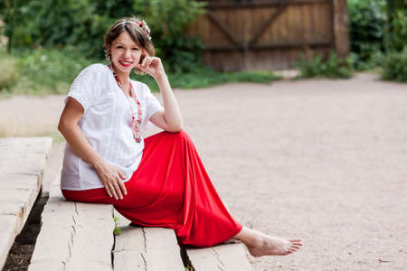 Ukrainian pregnant woman wear traditional embroidered shirt. Location in traditional ukrainian village. Pregnancy concept.の写真素材