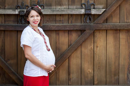 Ukrainian pregnant woman wear traditional embroidered shirt. Location in traditional ukrainian village. Pregnancy concept.の写真素材