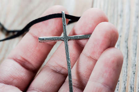 Silver christian cross in hand. Religious concept.の写真素材