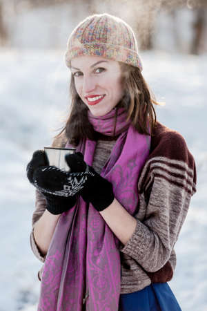 Cheerful girl drinking hot tea with steam outdoor.Winter sport and leisure concept.