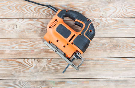 Electric jigsaw on a wooden table. Work tools concept.