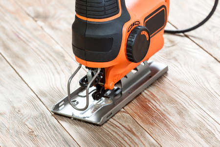Electric jigsaw on a wooden table. Work tools concept.