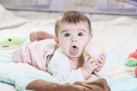 Beautiful newborn baby girl playing on the colorful rug.