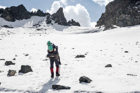 Hiker moving on land full of ice and snow at Tien Shan mountains, central asia, Kyrgyzstan. Climbing and mountaineering concept.の写真素材