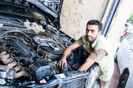 Adana, Turkey - September 15, 2011: An unknown mechanic full of dirt, repairs engine of an old car.のeditorial素材