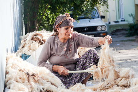 Adiyaman, Turkey - September 17, 2011: An unknown women processing wool on street, all workers are Kurdish nationality, and they wear their national clothes.のeditorial素材