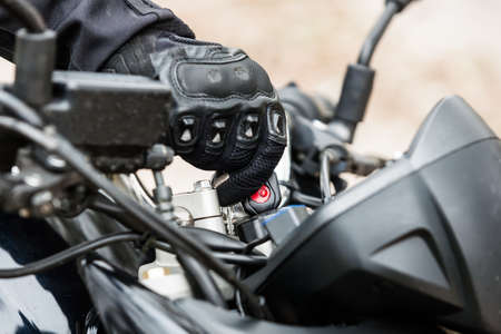 Biker starting the engine of his motorcycle, close-up on hands. Transportation concept.の写真素材