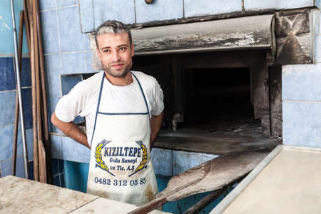 Mardin, Turkey - September 20, 2011: An unknown baker in a traditional Turkish bakery, making hand-made bread cooked on fire.のeditorial素材