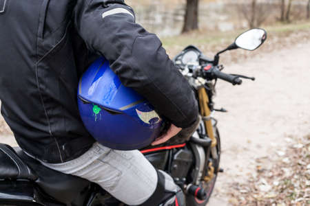 Biker sitting on motorcycle on an empty road, close-up view on legs. Transportation concept.