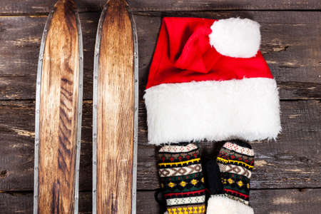 Overhead view of retro ski accessories placed on old rustic wooden table. Items included old retro wooden ski, gloves and hat. Winter sport leisure time concept.の写真素材