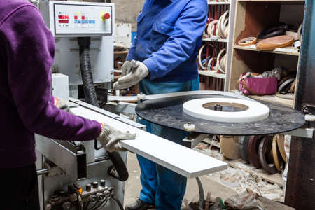 Workers using edger machine to make furniture at carpenters workshop. Handmade business at small...