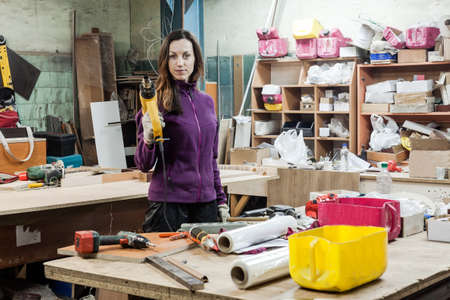Women worker using instruments to make furniture at carpenters workshop. Handmade business at small...