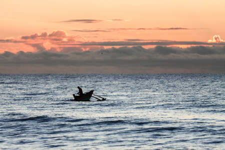 Traditional fishing boat with fisherman at sunrise.の写真素材